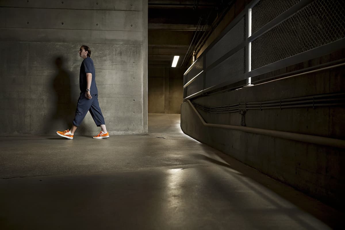 Nurse in navy scrubs and orange and white sneakers walking through a hospital parking garage